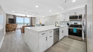A modern kitchen with white cabinetry, stainless steel appliances, and a large island.