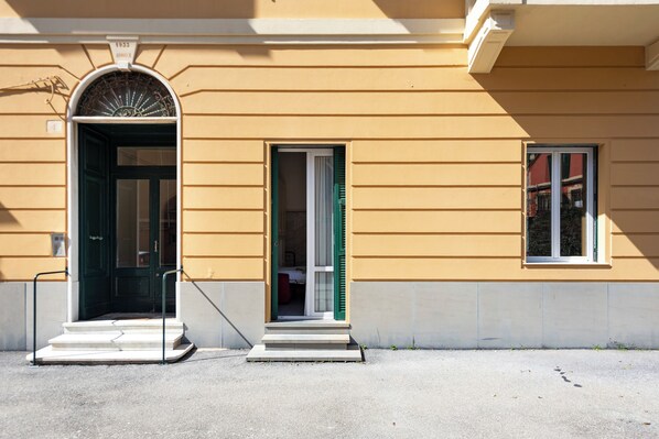 A building with a yellow facade, a green door, and a small window. - Apartment Vernazzola In Genova (Genoa)