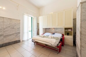 A bedroom with a bed, a wardrobe, and a door leading to a balcony. - Apartment Vernazzola In Genova (Genoa)