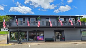 A two-story building with multiple American flags on the balcony. - Cambrian & Co. Downtown Loft Stylish, Sophisticated, Charm (Taylors Falls)