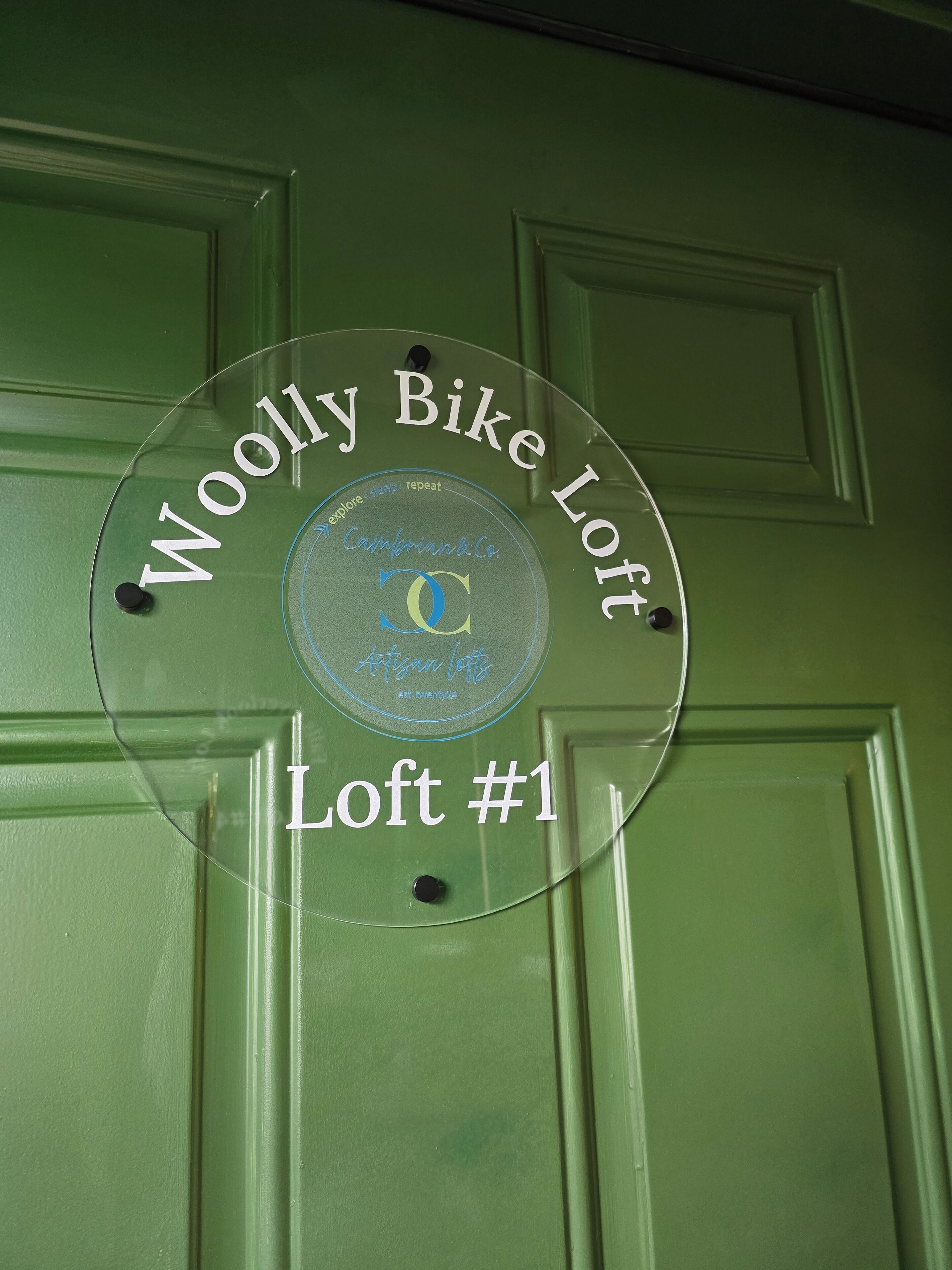A door with a circular sign indicating "Woolly Bike Loft Loft #1".