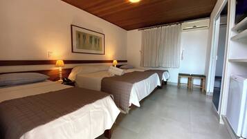 Quarto de hotel com duas camas, teto de madeira, um quadro na parede e uma janela com cortinas.