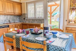 A kitchen with wooden cabinets, a tiled backsplash, and a table set for dining with various dishes and a teapot.