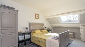 Un dormitorio con cama, armario, escritorio y tragaluz.