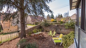 Un patio con muebles de exterior, un árbol y un muro de piedra.
