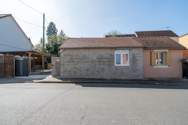 A small, single-story building with a tiled roof and a small window with shutters.
