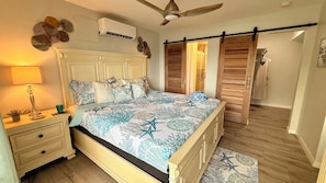 Un dormitorio con cama, mesita de noche, lámpara y ventilador de techo.