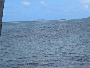 Une vue sur l’océan, avec une île lointaine et un ciel dégagé.
