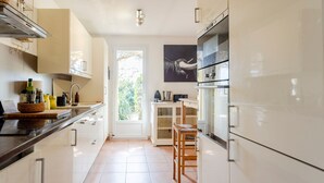 Eine moderne Küche mit weißen Schränken, einem großen Fenster und einer Tür zum Essbereich.