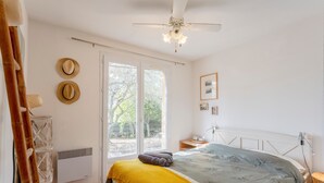 Ein Schlafzimmer mit einem Bett, einem Deckenventilator, einem Fenster und einem Wandheizgerät.