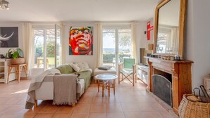 Ein geräumiges Wohnzimmer mit einer Couch, einem Kamin, einem großen Spiegel und einem Gemälde.