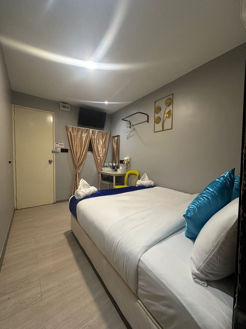 A hotel room with a bed, a desk, a chair, a TV, and a door.