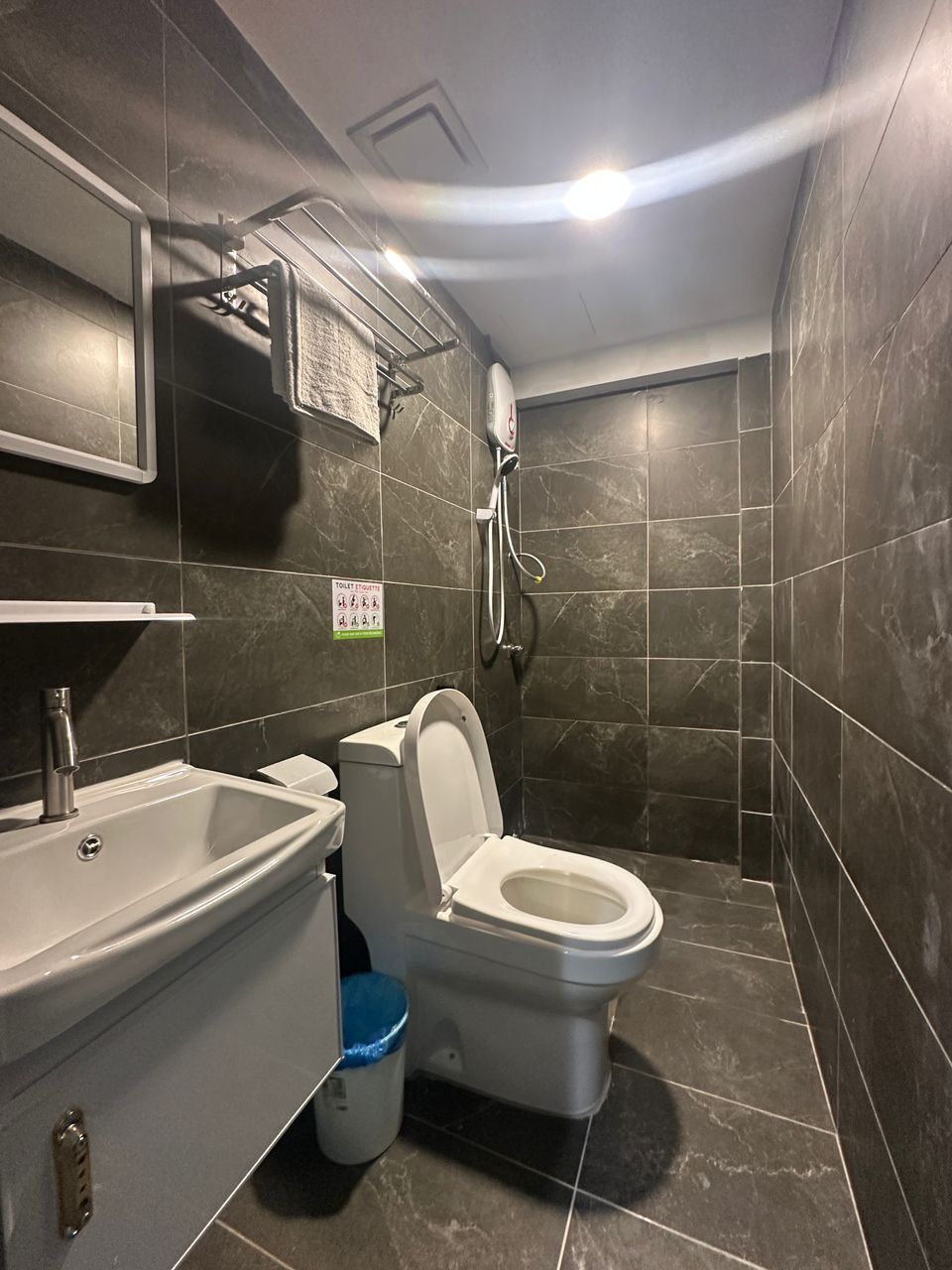 Un baño moderno con inodoro blanco, lavamanos y ducha.
