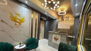 Un moderno vestíbulo de hotel con asientos tapizados en verde, una recepción y una pared de mármol con el logotipo del hotel.