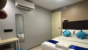 Una habitación de hotel moderna con cama, escritorio, silla, aire acondicionado y espejo.