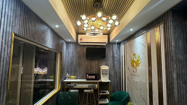 Un interior moderno con techo de madera, una lámpara de araña, zona de bar y asientos tapizados en verde.