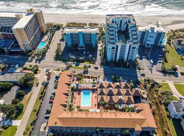 A coastal hotel complex with multiple high-rise buildings, a central pool area, and a beach view.