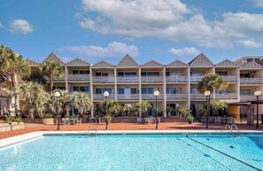 A hotel with a swimming pool, multiple balconies, and palm trees. - Beach Haven, Only 5-Star Reviews, 1st Floor Condo! (Myrtle Beach)