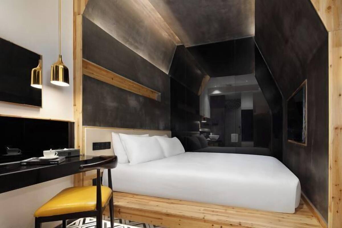 A modern hotel room with a bed, a desk, and a chair.