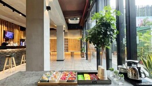 Eine moderne Hotellobby mit Rezeption, Sitzgelegenheiten und einem Buffet mit verschiedenen Speisen.
