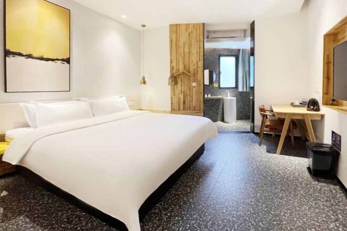 A modern hotel room with a large bed, a desk, and a bathroom.