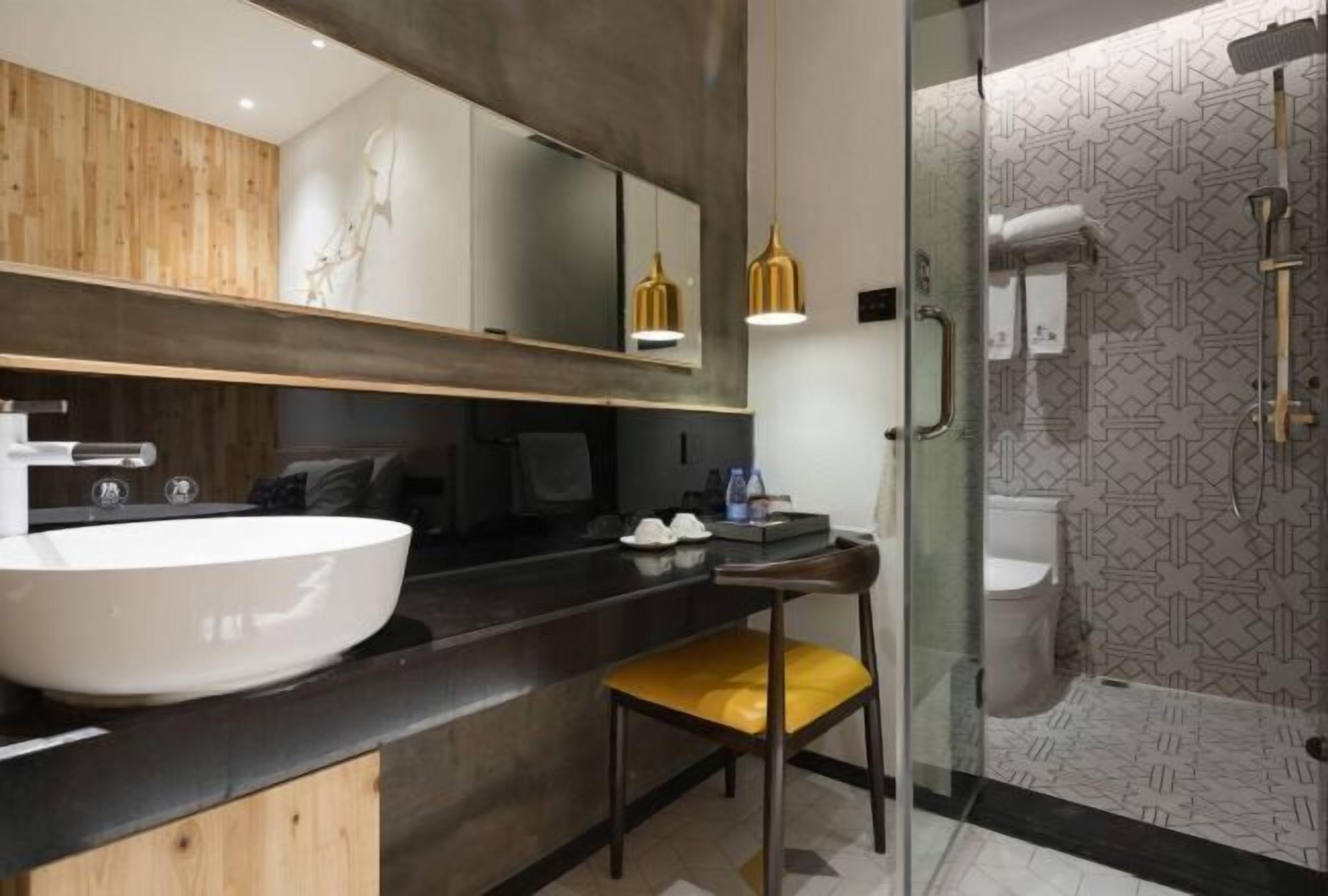A modern bathroom with a large white sink, a mirror, and a glass shower enclosure.