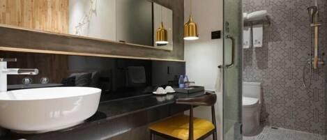 A modern bathroom with a large white sink, a mirror, and a glass shower enclosure.