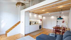 Una cocina moderna con armarios blancos, una escalera de madera y un comedor con una mesa y sillas.