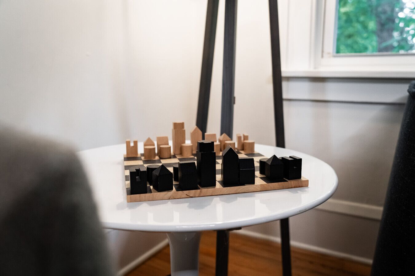 A wooden chessboard with black and brown pieces on a white table.