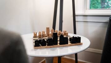 A wooden chessboard with black and brown pieces on a white table.