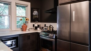 A modern kitchen with stainless steel appliances, a window with a view of greenery, and a decorative vase with flowers.