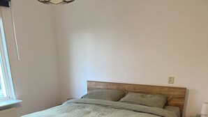 Een net opgemaakt bed met een houten hoofdbord en een groene dekbedovertrek.