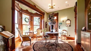 A spacious room with a large wooden floor, a round table with chairs, a chandelier, and a large window with a wreath. - A Country Retreat at Airy Knob Farm (Greencastle)
