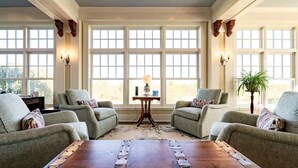 A spacious living room with four armchairs, a wooden coffee table, and large windows providing natural light. - A Country Retreat at Airy Knob Farm (Greencastle)