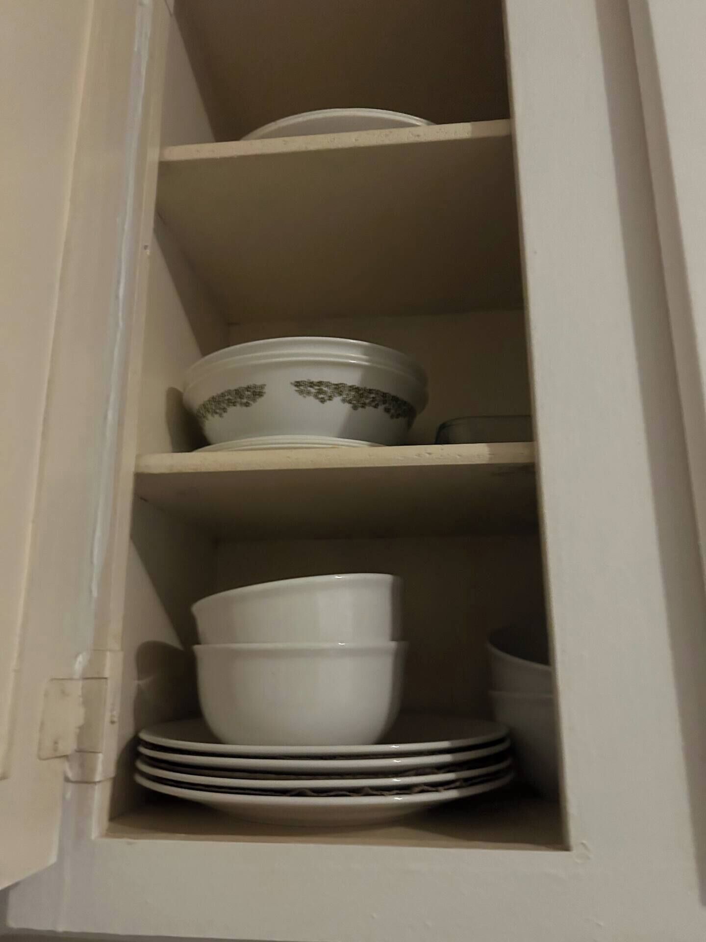 Ein Schrank mit Regalen voller weißer Geschirr und Schüsseln.