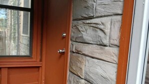A wooden door with a glass window, a stone wall, and a wooden floor. - Big House on Broadway (Jacksonville)