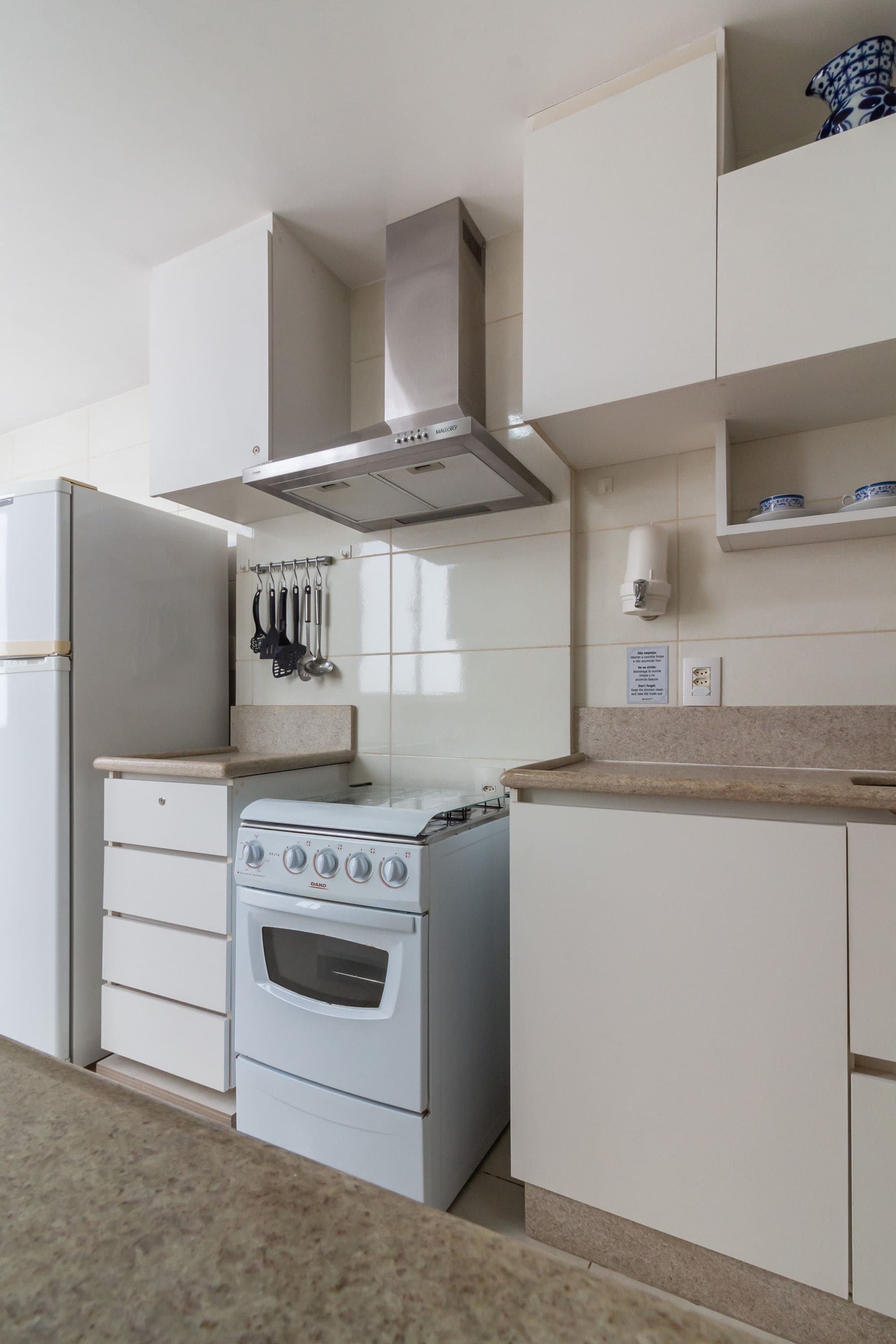 A kitchen with white cabinets, a stove, and a hanging pot rack.