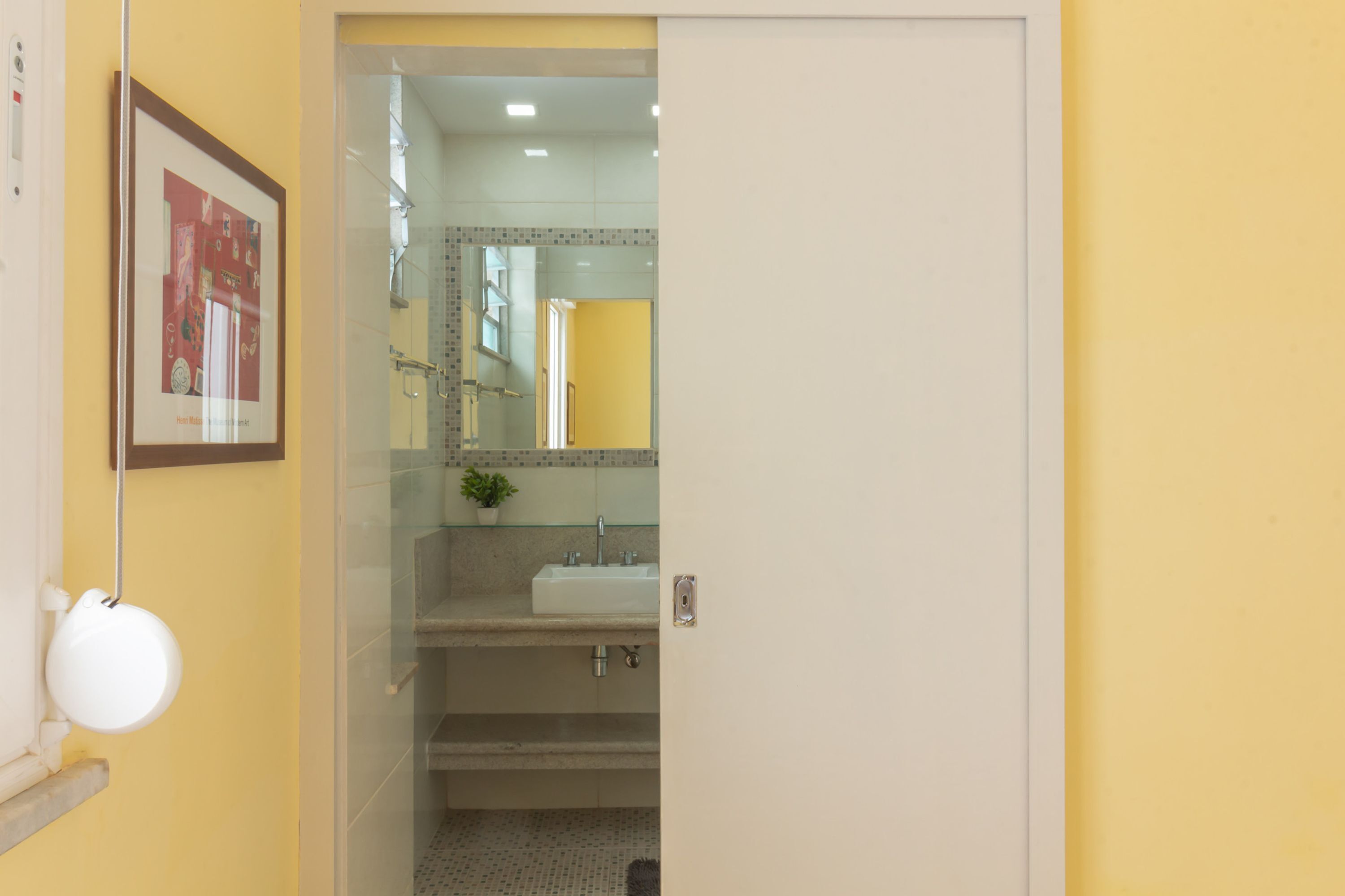A bathroom with a glass shower enclosure, a sink, and a framed picture on the wall.