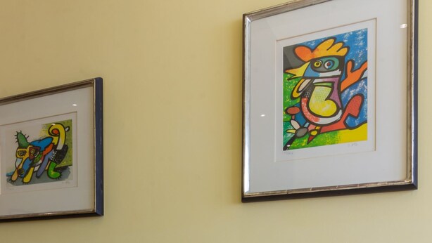 Un canapé blanc agrémenté de coussins colorés et deux œuvres d’art encadrées accrochées au mur.