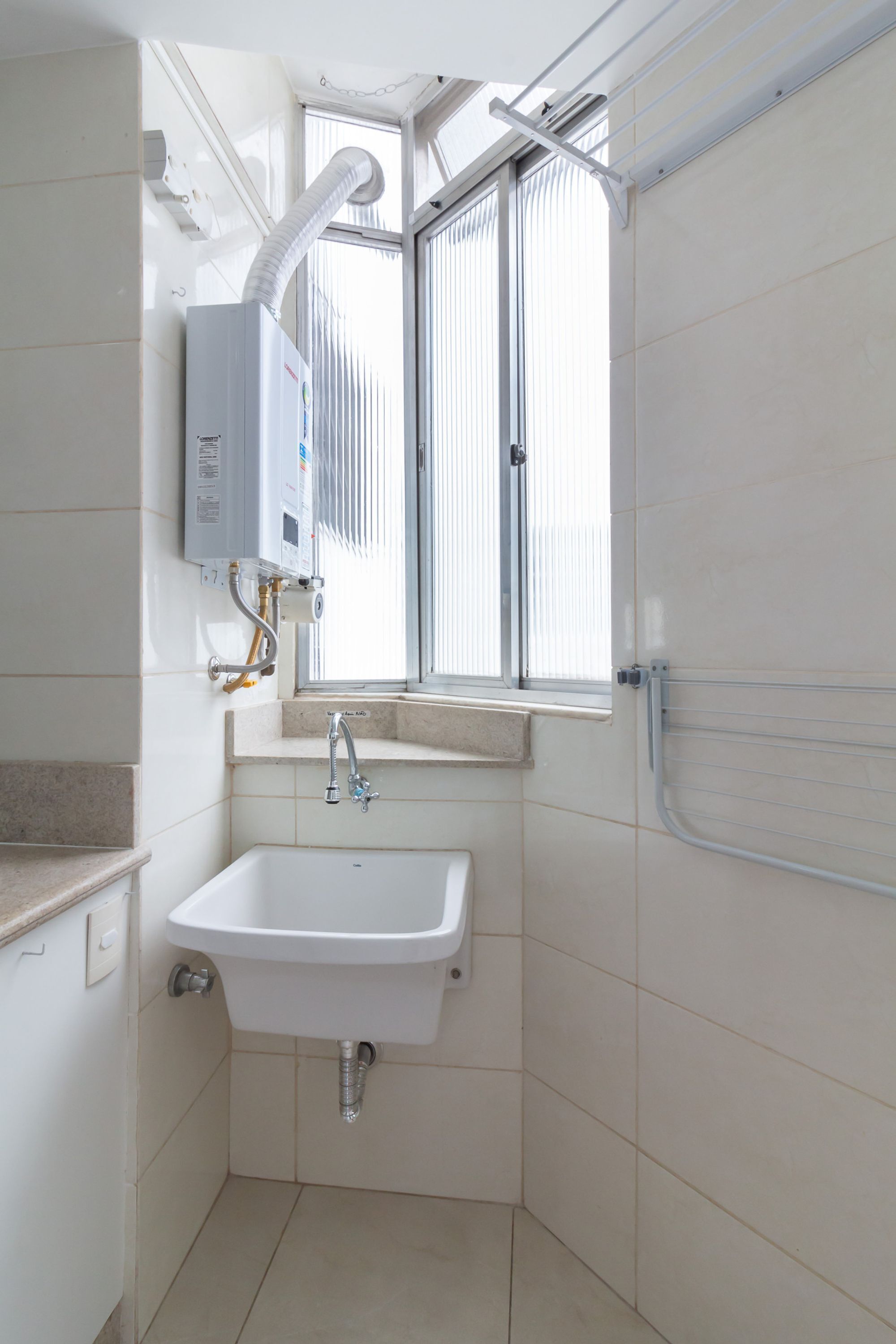 A small bathroom with a white sink, a window, and a towel rack.