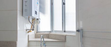 A small bathroom with a white sink, a window, and a towel rack.