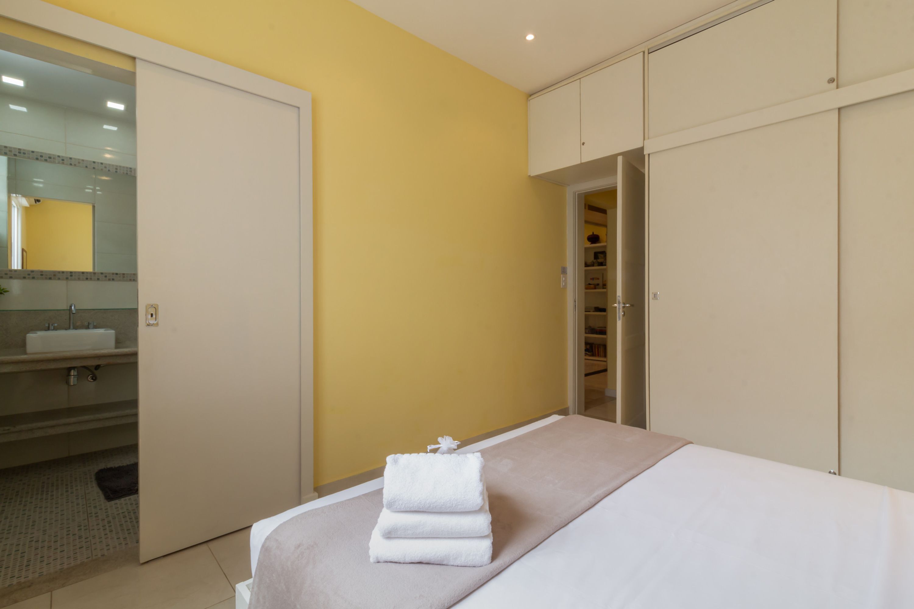 Een hotelkamer met een bed, een badkamer met een wastafel en een inloopkast.