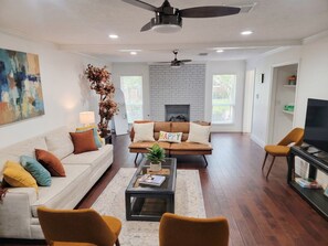 A modern living room with a fireplace, two sofas, a coffee table, and a television.