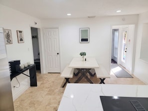 A modern kitchen with a white countertop, a black shelf, and a white dining table with benches. - Pool | BBQ | Game Room | Gym | Patio | Workspace (Houston)