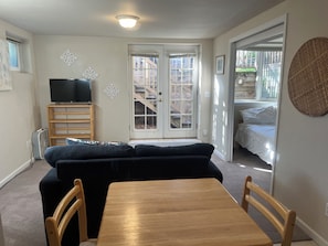 A compact living space with a sofa, a TV on a stand, a dining table, and a sliding glass door leading to a balcony. - Fabulous locale for light-filled mountainside apartment in charming Boulder. (Boulder)