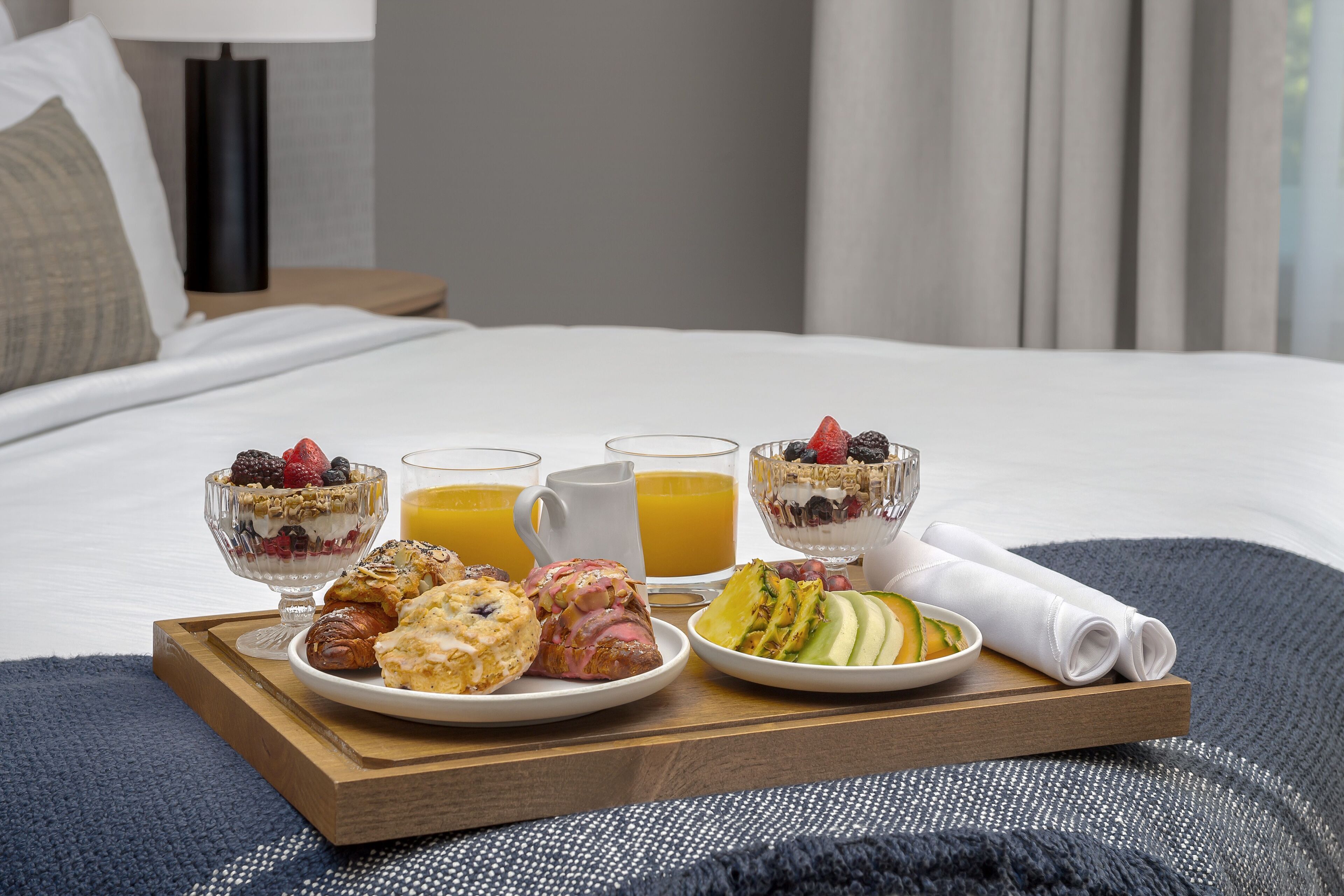 Bandeja de café da manhã sobre a cama, com diversos alimentos e bebidas.