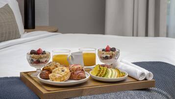 Bandeja de café da manhã sobre a cama, com diversos alimentos e bebidas.