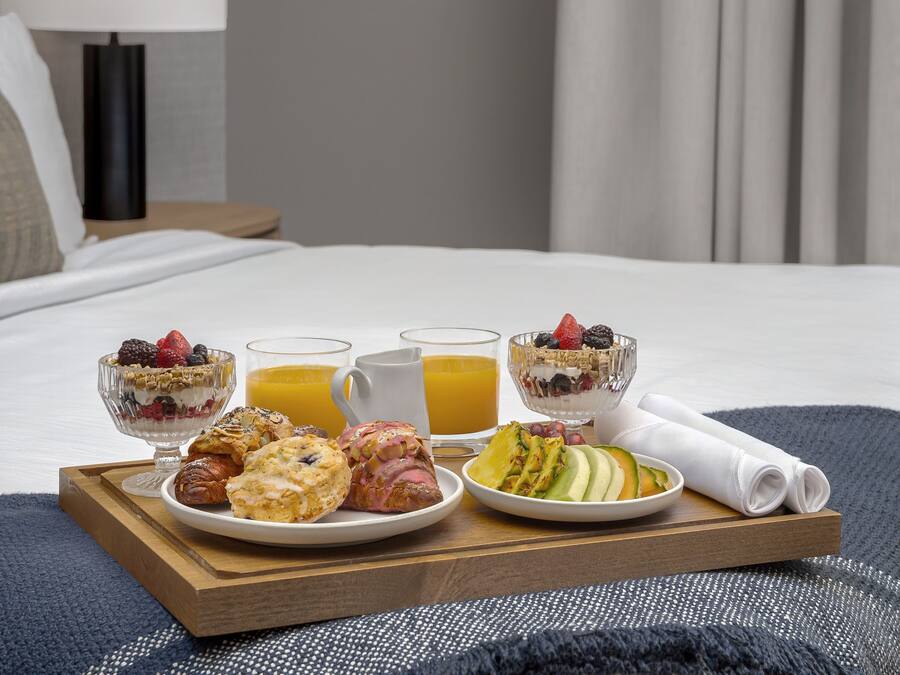 Bandeja de café da manhã sobre a cama, com diversos alimentos e bebidas.