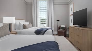 A hotel room with two beds, a television, a cabinet, and a window with curtains.