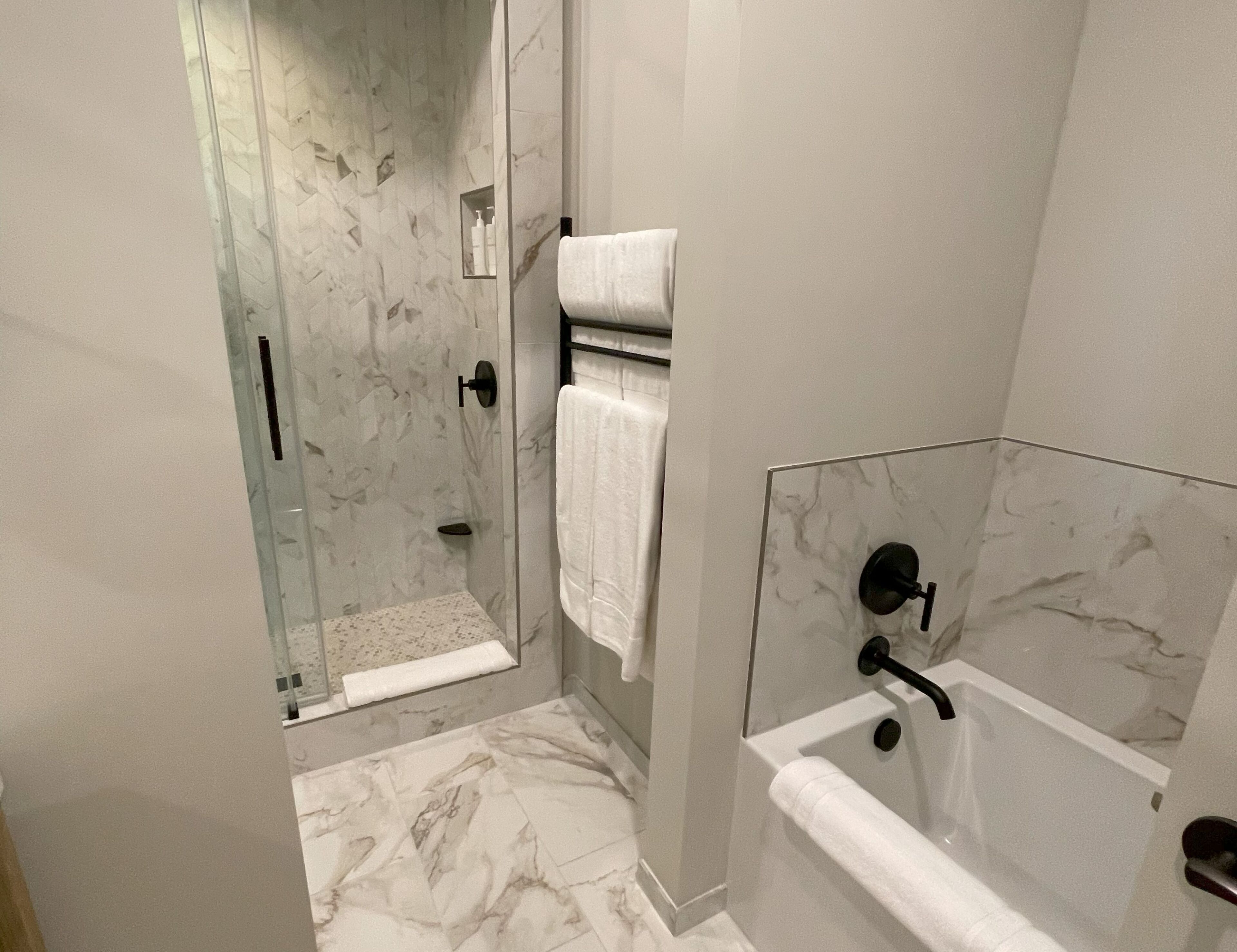 Un baño moderno con ducha envuelta en cristal, bañera y retrete.